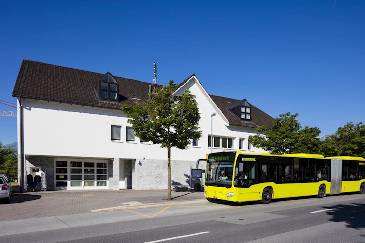Ein Gelenkbus in der Lime-Farbe der Liemobil hält vor dem Postgebäude Mauren.