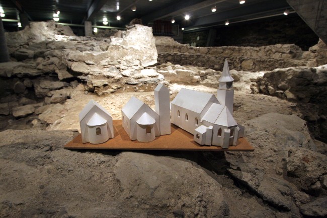 Modelle der Vorgängerkirchen stehen in den ausgegrabenen Mauerresten
